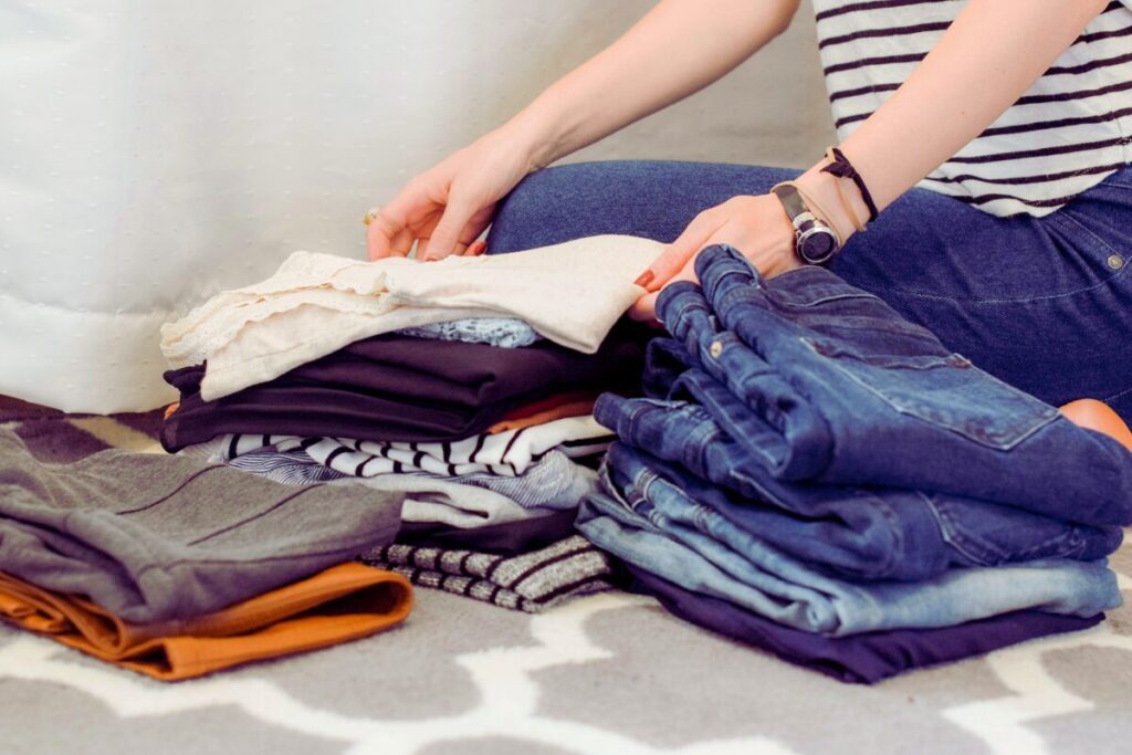 女性がたくさんの服を畳んでいる手元。