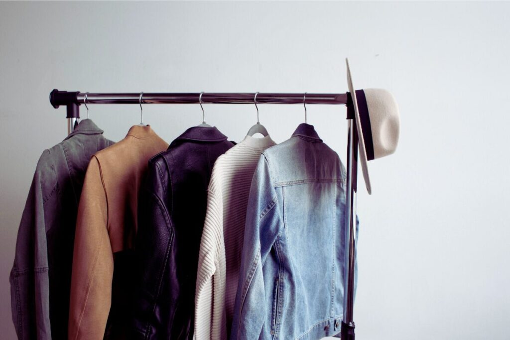ハンガーかけに服が5着かかっている。右側に帽子がかかっている写真。