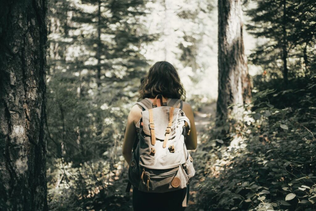 リュックを背負った女性が山道を歩いている後ろ姿