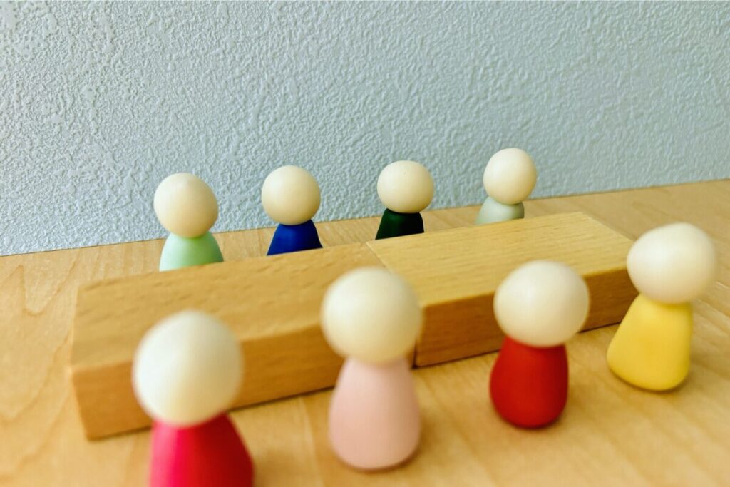 木で作った人が4対4で向かい合っているイメージ。