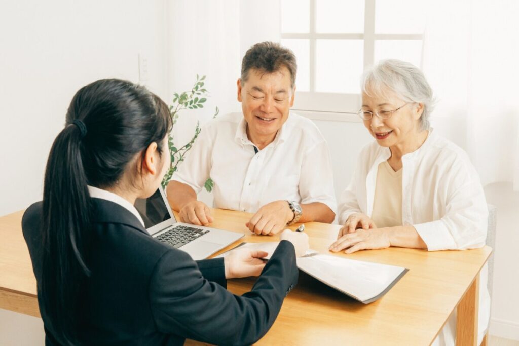 高齢の夫婦が笑顔で女性の説明を聞いている様子